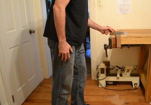 Showing better form while using a small patternmaker's saw with high hang.  The elbow has been raised by standing more upright, bringing the forearm into alignment with the wrist.  In practice, I would prefer to lean and crouch as shown in Figure 5, but angle the saw and/or lower the work.  I find that this engages more of the lower body, increasing power, accuracy, and comfort.